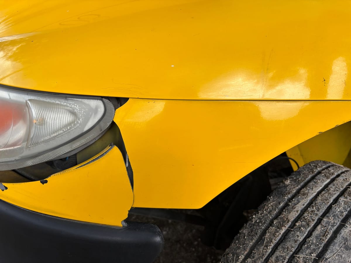 Close-up of collision damage on a vehicle's front bumper and headlight
