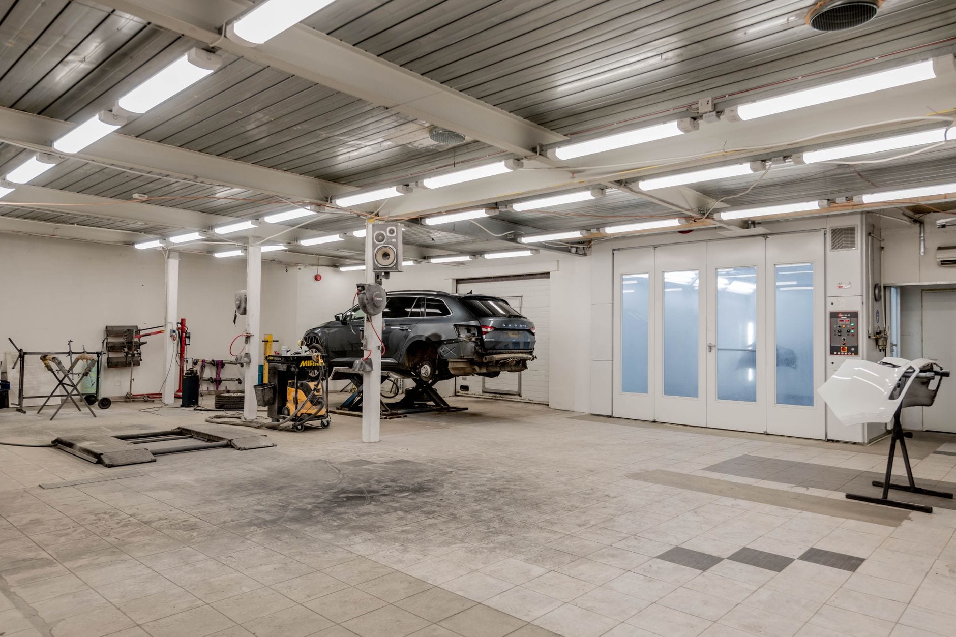 A vehicle on a lift inside a modern collision repair bay
